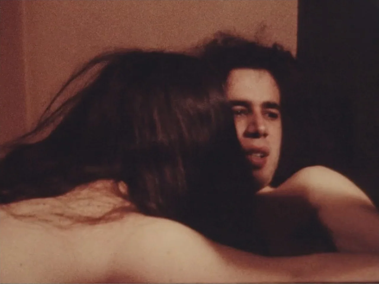 Don't Expect Too Much (2011) movie still: closeup — An interior bedroom space with warm lighting and a soft focus. Two individuals are close…
