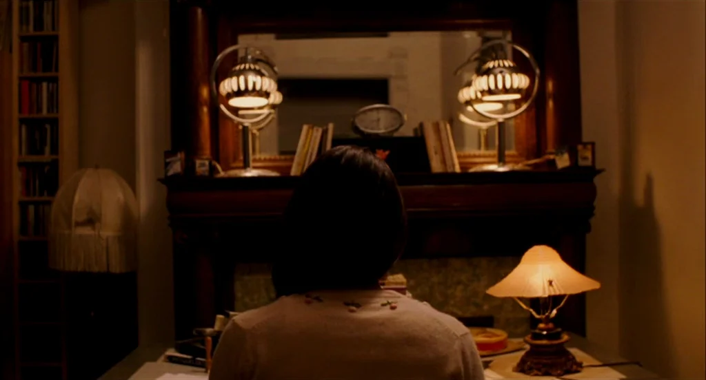 Heartbeats (Les Amours Imaginaires) (2010) movie still: medium — A dark study features a wooden mantel topped with dual lamps and a mirror. A woman…