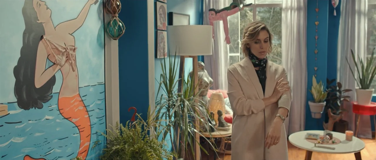 Cindy La Regia (2020) movie still: medium — A blue-walled living room decorated with houseplants, a large mermaid mural, and eclectic accessories. A…