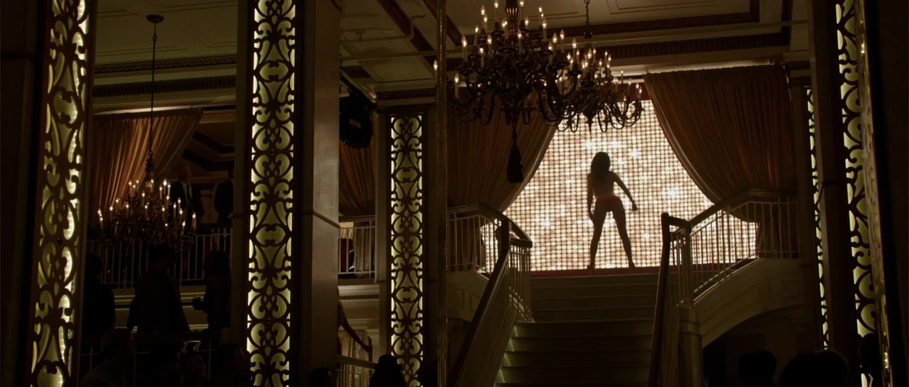 The Internship (2013) movie still: wide — A luxury club interior features a grand staircase leading to a glowing rear backdrop. A woman stands in…