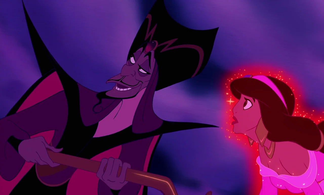 Aladdin (1992) movie still: medium — A dark, dimly lit environment suffused with deep purple and indigo shadows. A tall man in robes towers over a…