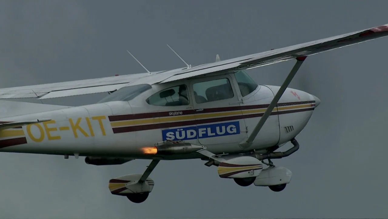 The Alps from Above: Symphony of Summits (2014) movie still: medium — A small light aircraft flies against a uniform overcast gray sky. Flames…