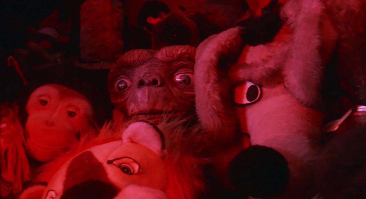 E.T. The Extra-Terrestrial (1982) movie still: closeup — A pile of stuffed animals including a figure resembling E.T. rests in the dark. The scene…