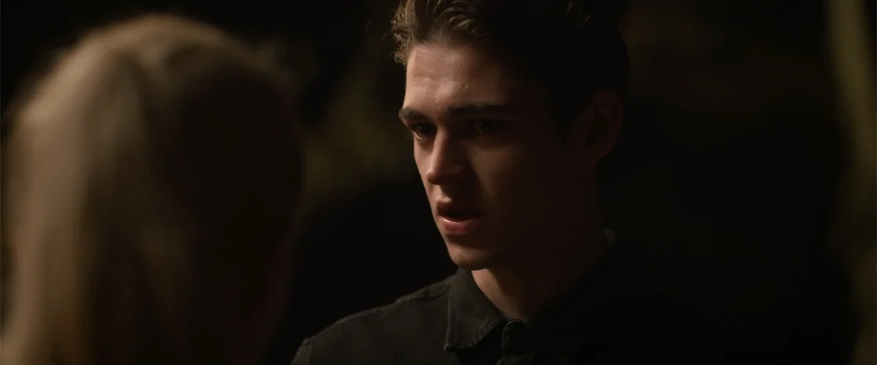 After Ever Happy (2022) movie still: closeup — A dark outdoor space at night with a blurred foreground silhouette of a person. A young man with…