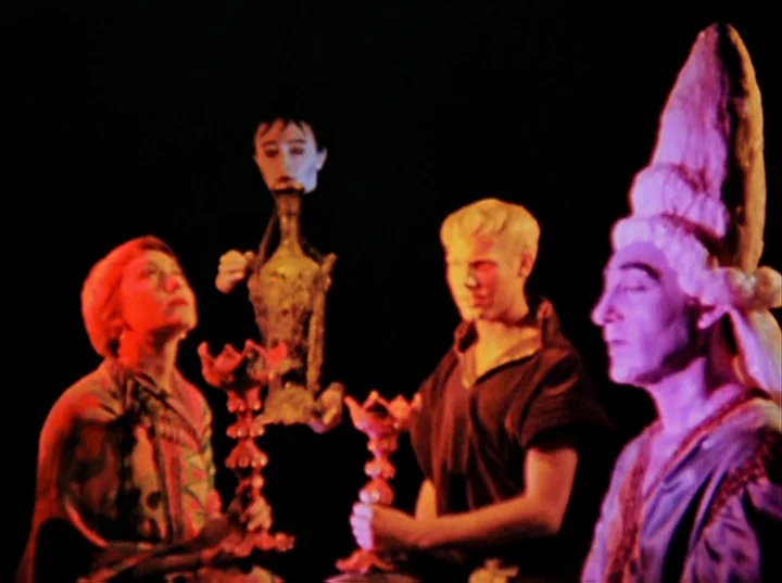Inauguration of the Pleasure Dome (1954) movie still: medium — A dark stage features three individuals holding ornate red candlesticks against a…