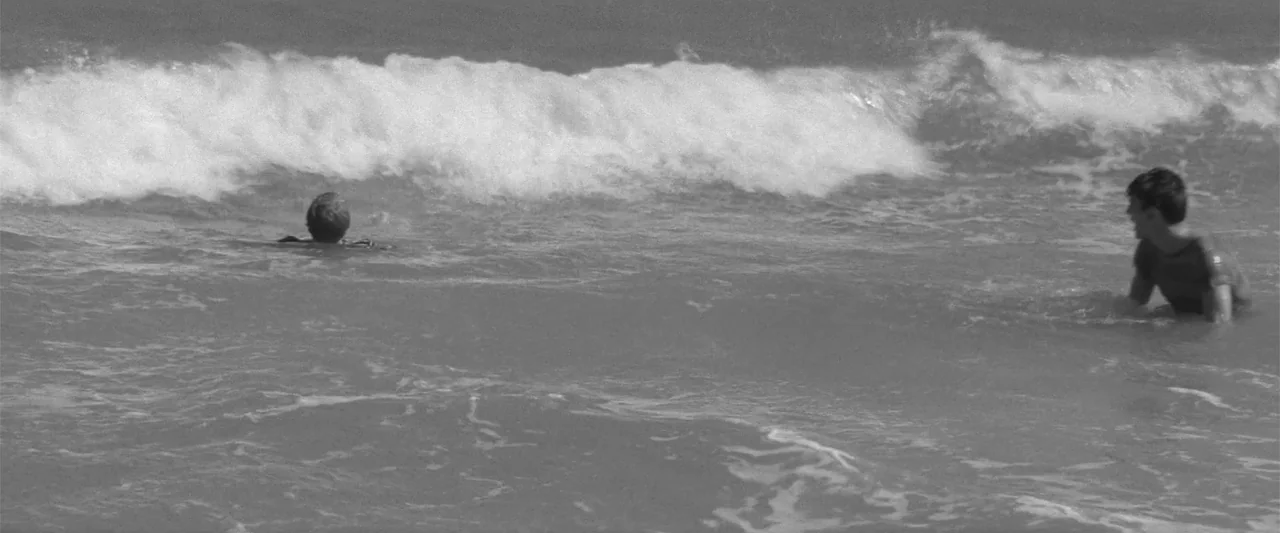 Jules and Jim (1962) movie still: wide — The ocean surface features active white-capped waves moving from left to right. Two people are partially…