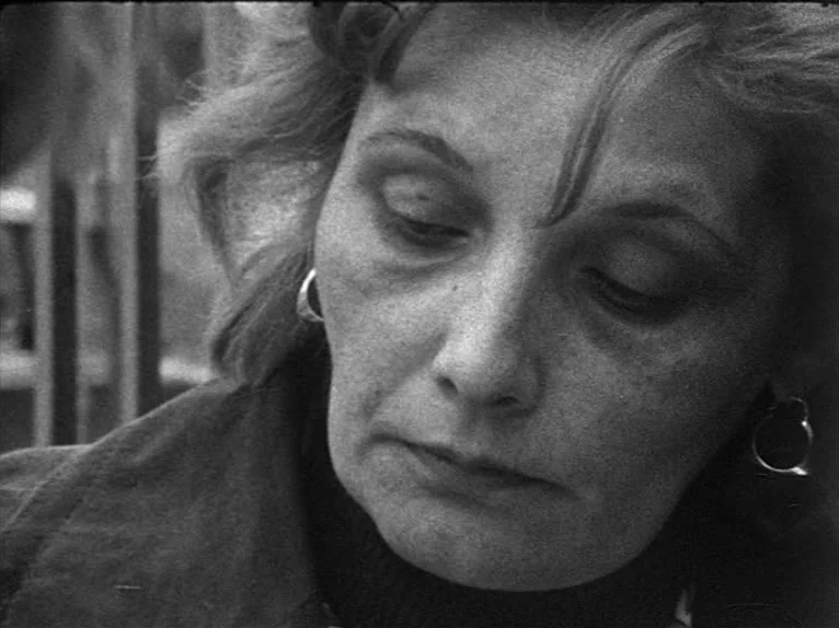 Family Nest (1979) movie still: closeup — A woman's face fills the frame, captured in a grainy black and white film style. She looks downward with…