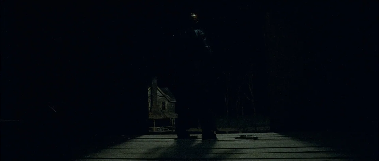 Blood Creek (2009) movie still: fullbody — A dark, wooden porch floor is illuminated by moonlight against a black background. A lone, silhouetted…