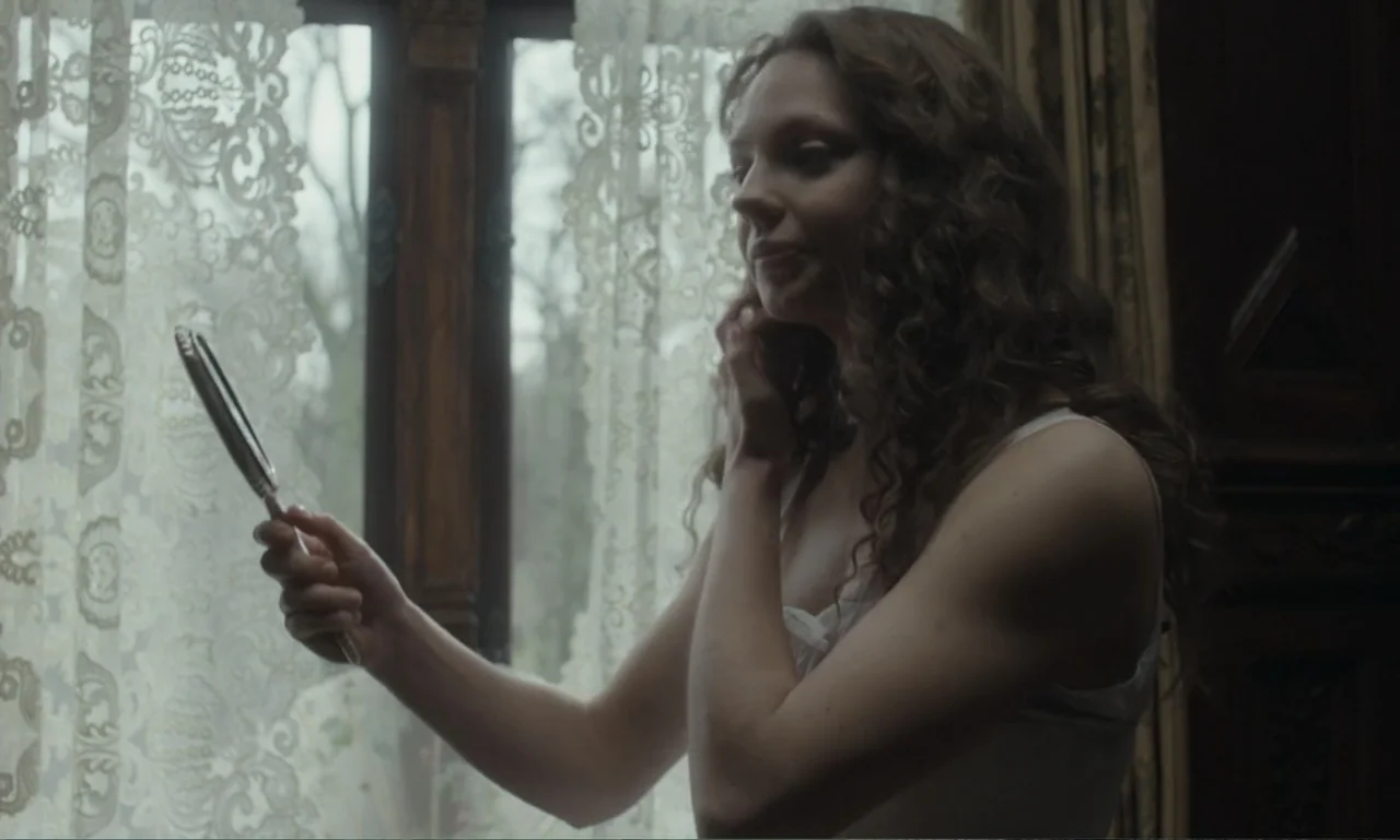 The Ugly Stepsister (2025) movie still: medium — A room features a large window draped in intricate white lace curtains. A young woman stands by the…