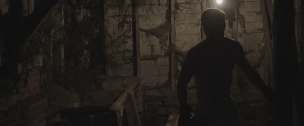 Behind the Line: Escape to Dunkirk (2020) movie still: medium — An abandoned, cluttered cellar features dark wooden walls covered in heavy cobwebs…