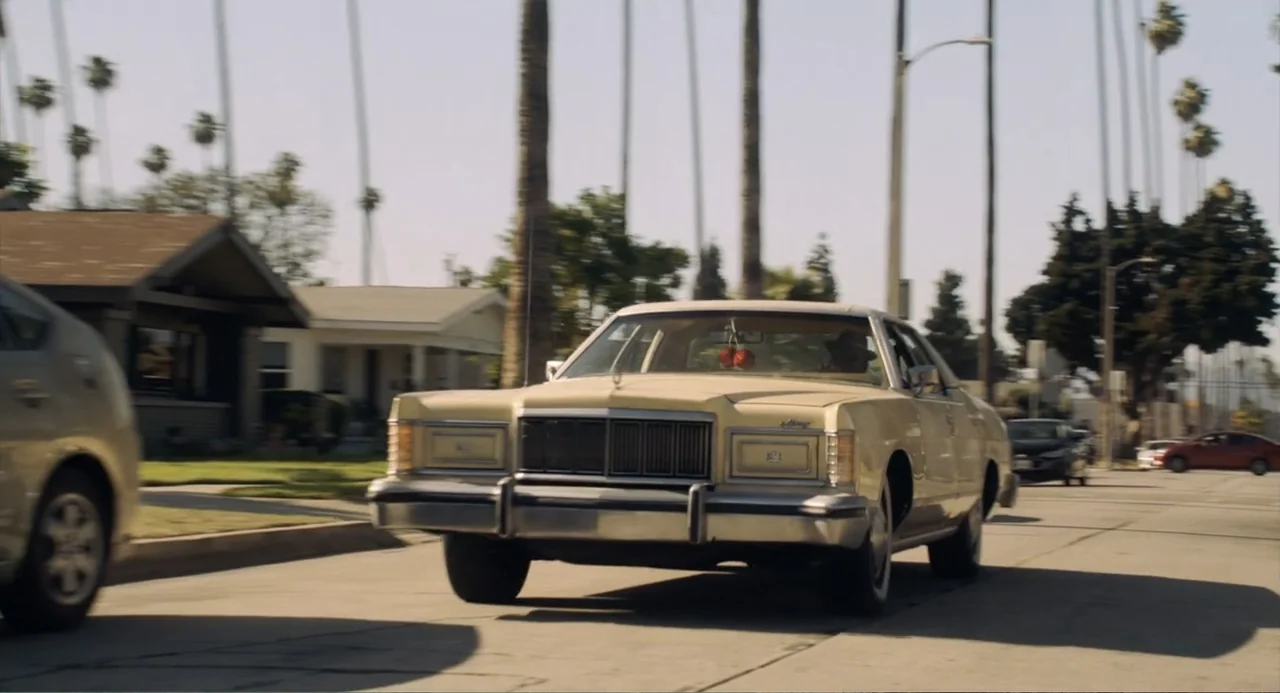 House Party (1990) movie still: medium — A residential street lined with tall palm trees and single-family houses. A man drives a cream-colored…