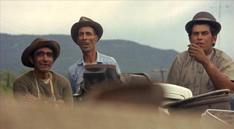 Easy Rider (1969) movie still: medium — Three men wearing hats stand in a dusty rural landscape under an overcast sky. The men appear to be gathered…