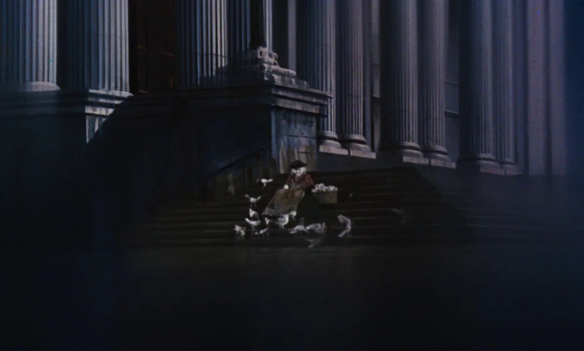 Mary Poppins (1964) movie still: wide — A dark, classical stone structure with tall columns and expansive steps at night. An elderly woman sits on…