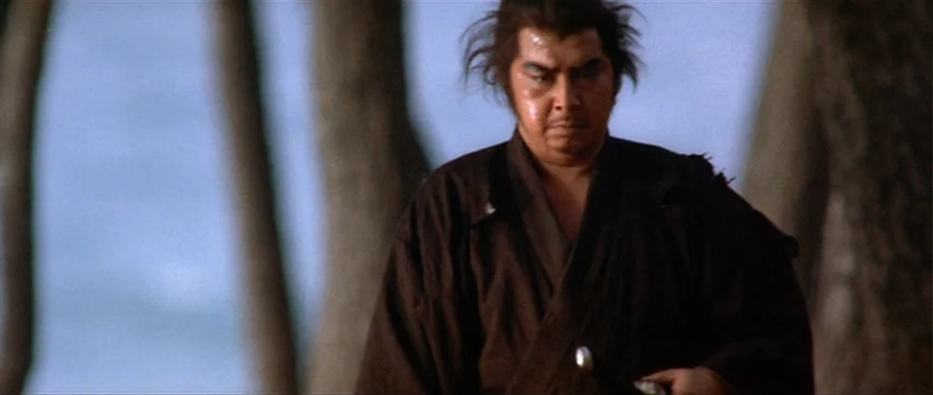 Lone Wolf: Baby Cart at the River Styx (1972) movie still: medium — A dense grove features blurred tree trunks framing the subject against a pale…