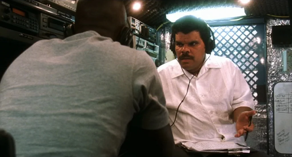 Traffic (2000) movie still: medium — A cramped surveillance van interior features walls lined with reflective silver insulation material. A man with…