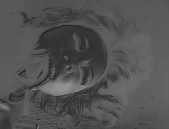 Funeral Parade of Roses (1969) movie still: closeup — An inverted negative film frame showing a person's head and neck area. The subject rests…