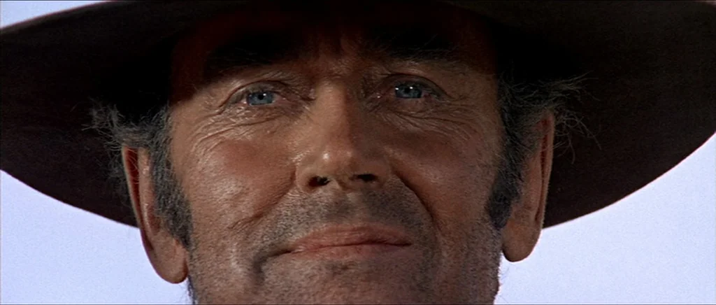 Once Upon A Time In The West (1968) movie still: closeup — A man's face fills the frame against an out-of-focus, light-colored background. He wears…