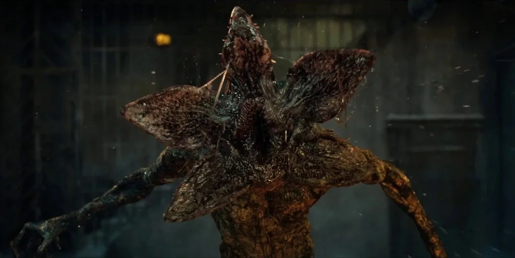 Stranger Things (2016) movie still: closeup — A dark, dimly lit laboratory space with metal structures and dust particles. A monstrous creature…