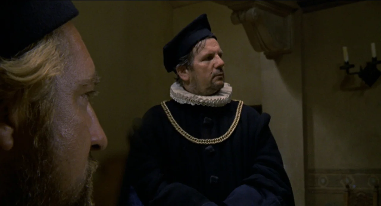 Beatrice Cenci (1969) movie still: medium — A dimly lit room with stone-like walls features two men in historical clothing. A man with a white ruff…