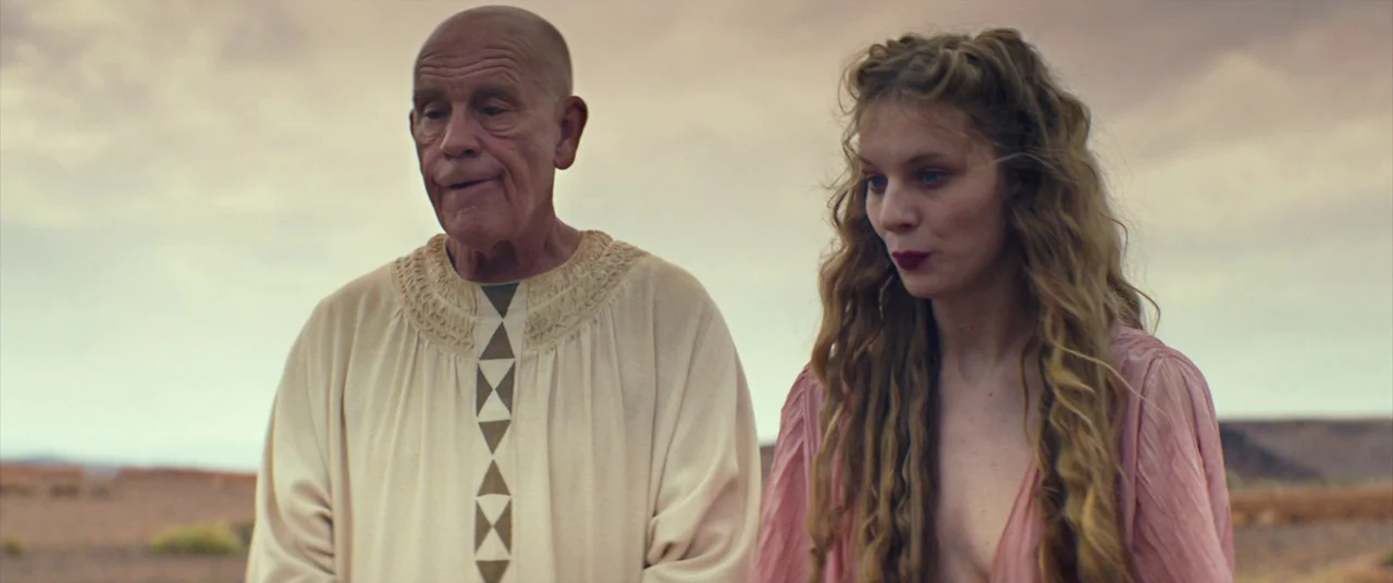 Seneca: On The Creation Of Earthquakes (2023) movie still: medium — A desolate desert landscape extends to the horizon under a cloudy sky. An older…
