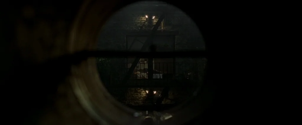 Panic Room (2002) movie still: wide — A dark brick wall featuring a metal fire escape structure at night. The view is framed through a circular,…