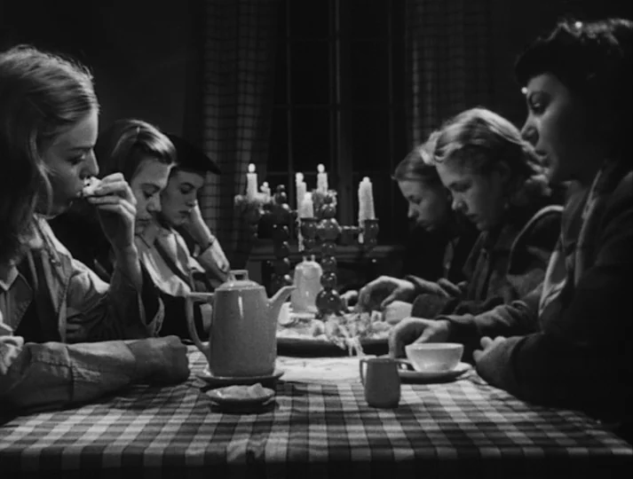 Port of Call (1948) movie still: medium — A group of young women sit around a checkered tablecloth in a dark room. They gather around a central…