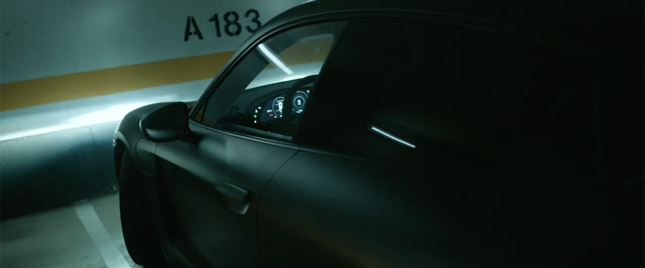 Den of Thieves 2: Pantera (2025) movie still: medium — A dark matte-finish sports car is parked in a concrete parking garage at night. The vehicle…