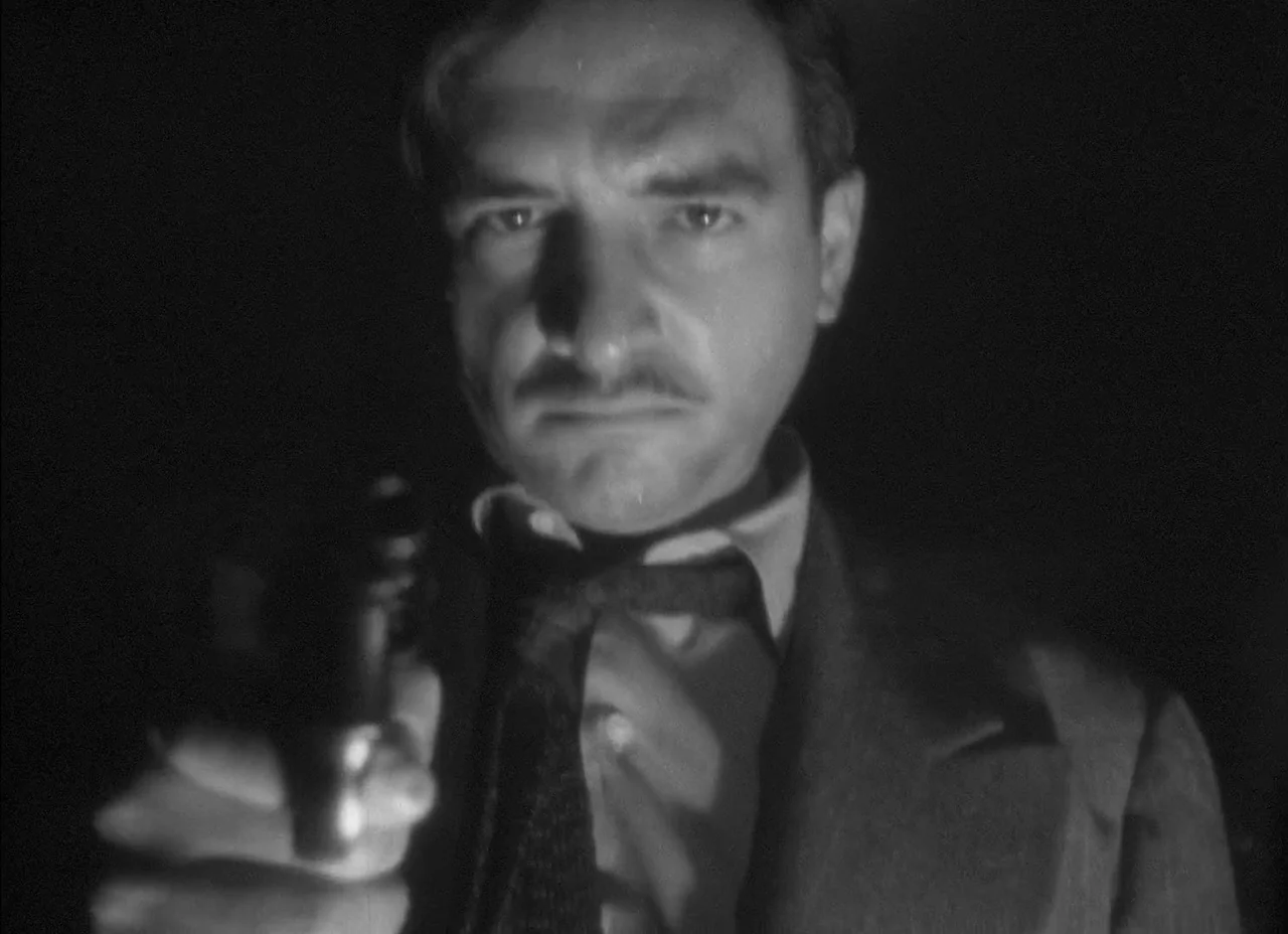 The Amazing Mr. X (1948) movie still: closeup — A dark space with no visible architectural details or background elements. A man points a small…