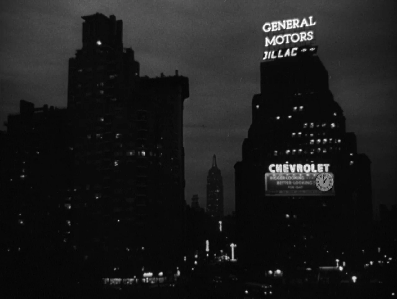 The Naked City (1948) movie still: establishing — A nighttime view of New York City skyscrapers with glowing neon advertising signs visible. The…