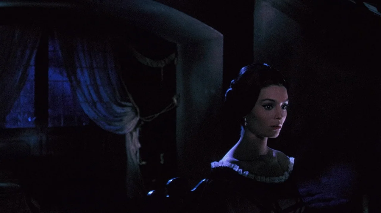 The Whip and The Body (1963) movie still: medium — A dimly lit room features a window with sheer curtains at the left. A woman wearing a…