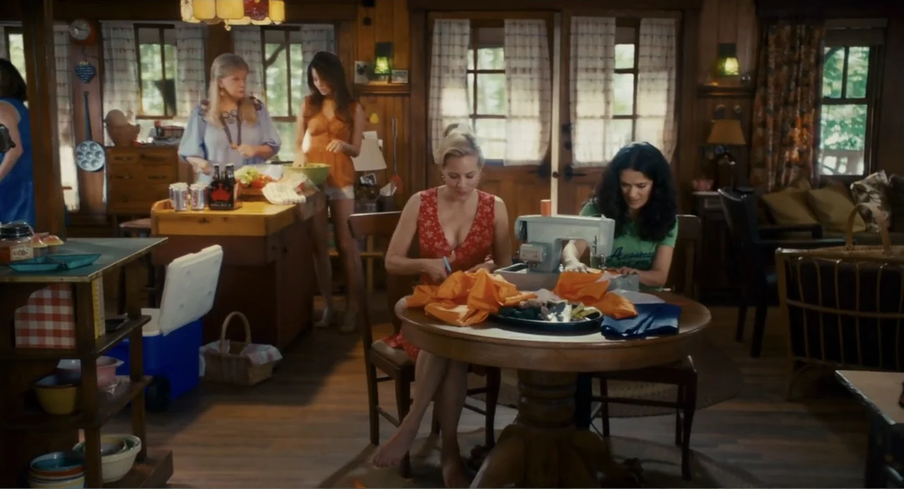 Grown Ups (2010) movie still: medium — A rustic cottage interior features wooden paneling, a kitchen island, and a sewing area. Four adult women…