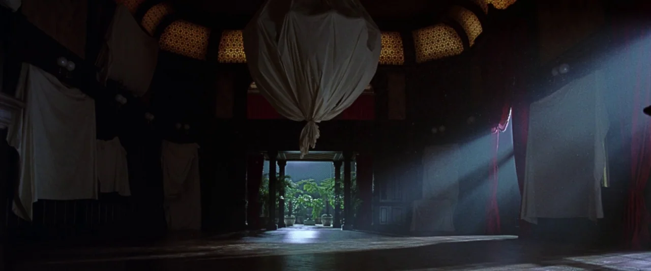 The Age of Innocence (1993) movie still: establishing — A darkened, cavernous room contains furniture draped in large white sheets for protection. A…