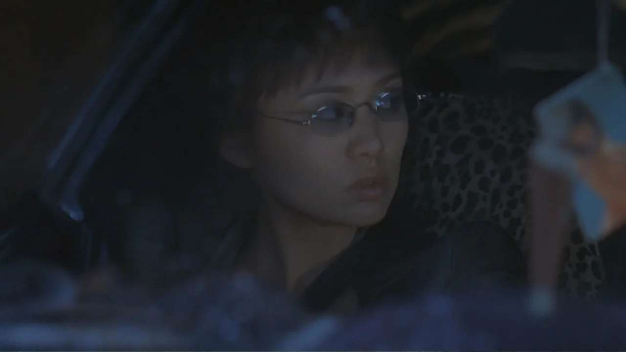 The Art of War (2000) movie still: closeup — The interior of a dark car at night with a leopard print seat cover. A woman with short dark hair and…
