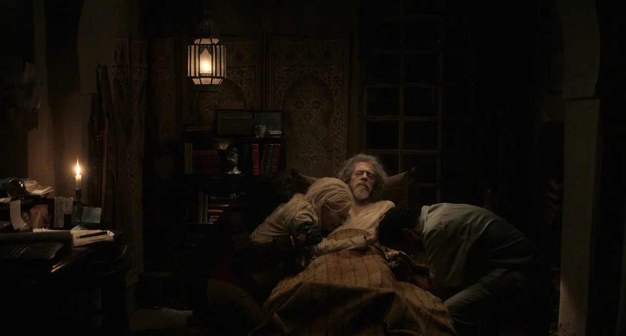 Only Lovers Left Alive (2013) movie still: medium — A dimly lit room contains a bed where an elderly man lies under covers. Three people surround…