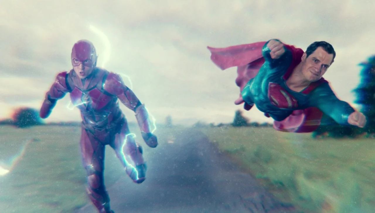 Justice League (2017) movie still: fullbody — Two superheroes travel at high speed across a wide, overcast open field landscape. The Flash runs in…