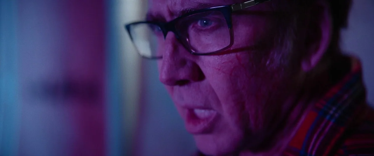 Colour Out of Space (2020) movie still: closeup — A close portrait of a man in a dimly lit, neon-saturated indoor space. He looks slightly away from…