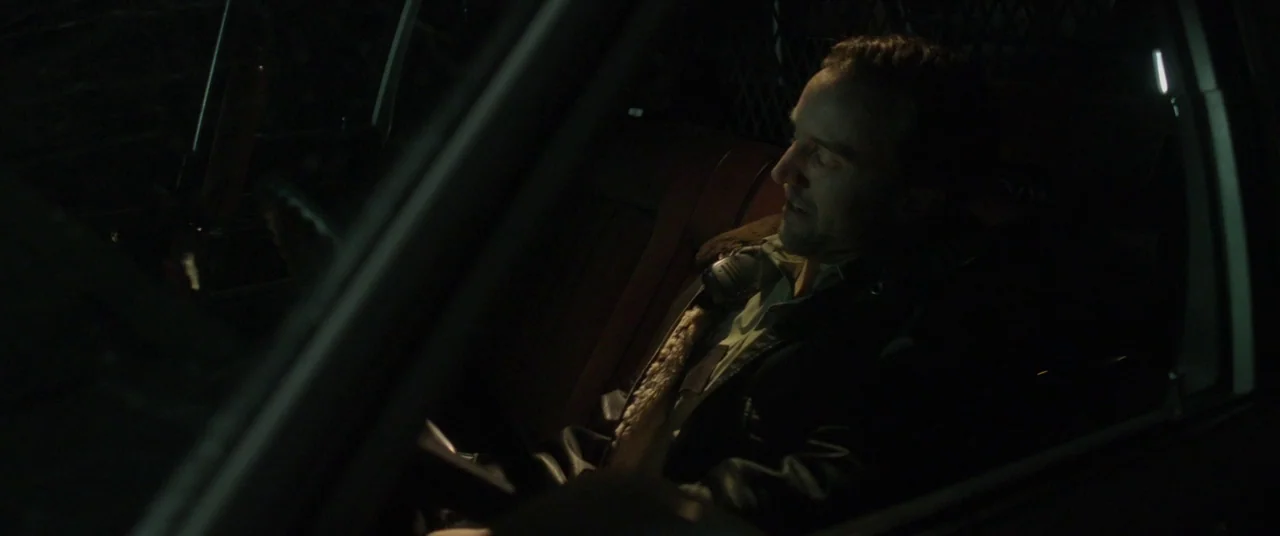 The Void (2016) movie still: medium — A dark, cramped interior of a police vehicle at night. A uniformed officer sits in the driver's seat.