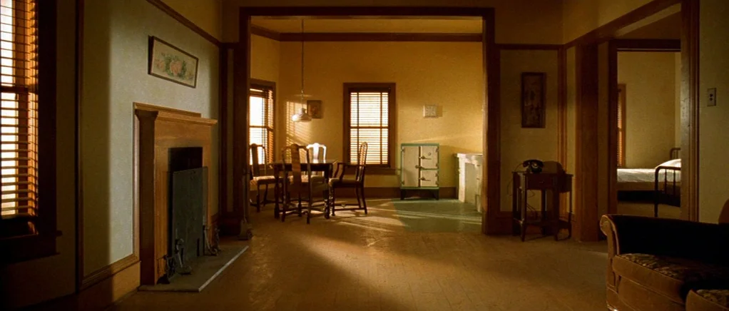 King of the Hill (1993) movie still: establishing — A quiet vintage interior features wooden floors, a fireplace, and connected living and dining…
