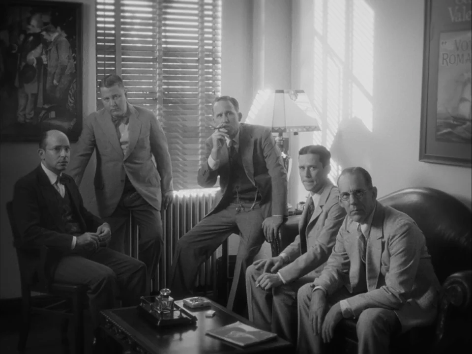 The Artist (2011) movie still: medium — An office room with vertical blinds and a framed painting on the wall. Five men in 1930s suits gather in the…