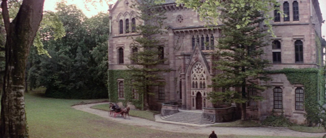 The House That Screamed (1969) movie still: establishing — A large stone manor features gothic arches, ivy-covered walls, and a grand arched…