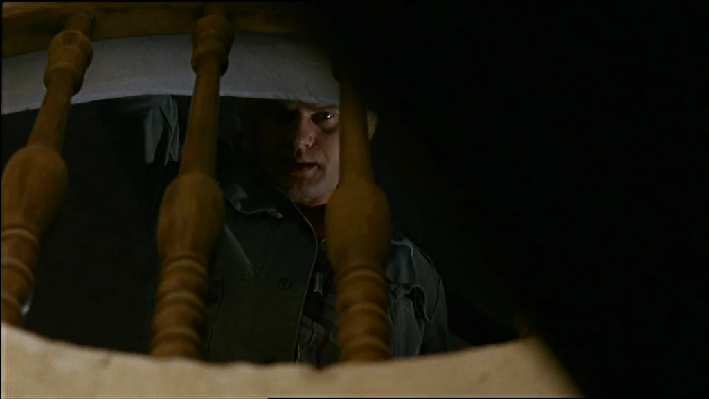 Chinese Roulette (1976) movie still: closeup — A dark stairwell viewed from the perspective of someone looking down through wooden railings. A man…