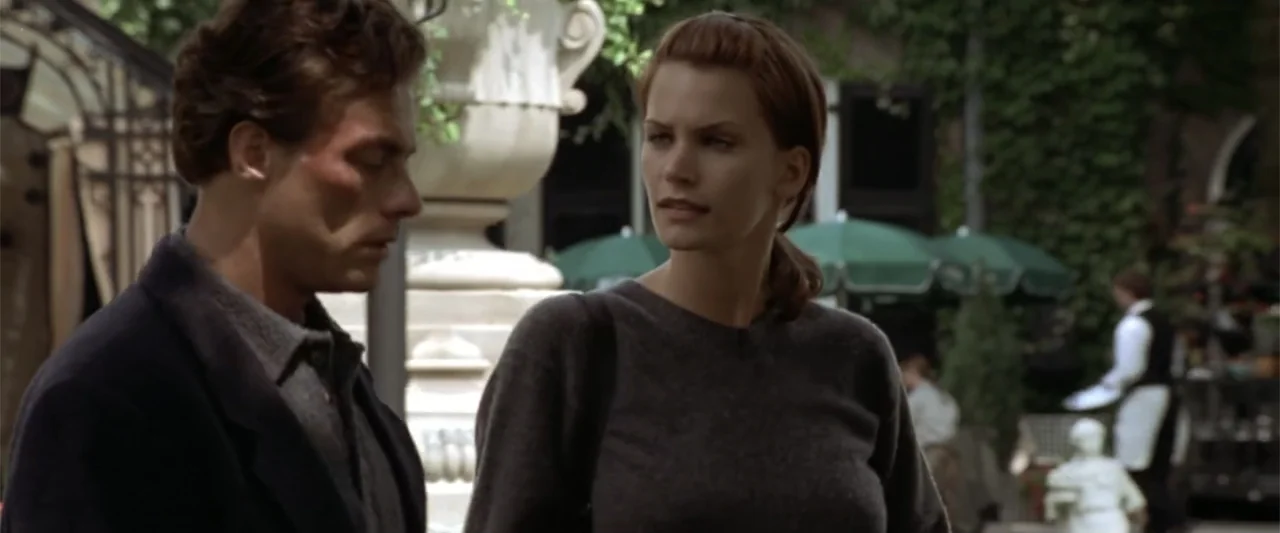 Maximum Risk (1996) movie still: medium — An outdoor courtyard area features stone pillars and green umbrellas in the background. A man and a woman…