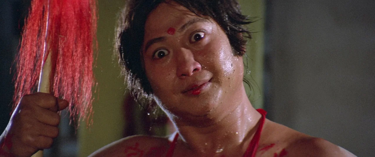 Encounter of the Spooky Kind (1980) movie still: closeup — A man stands in an interior space while covered in perspiration and red markings. He…