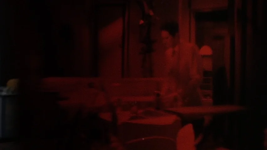 Four Times that Night (1971) movie still: medium — A dimly lit room is bathed in a dark monochromatic red light. A person stands upright in the…