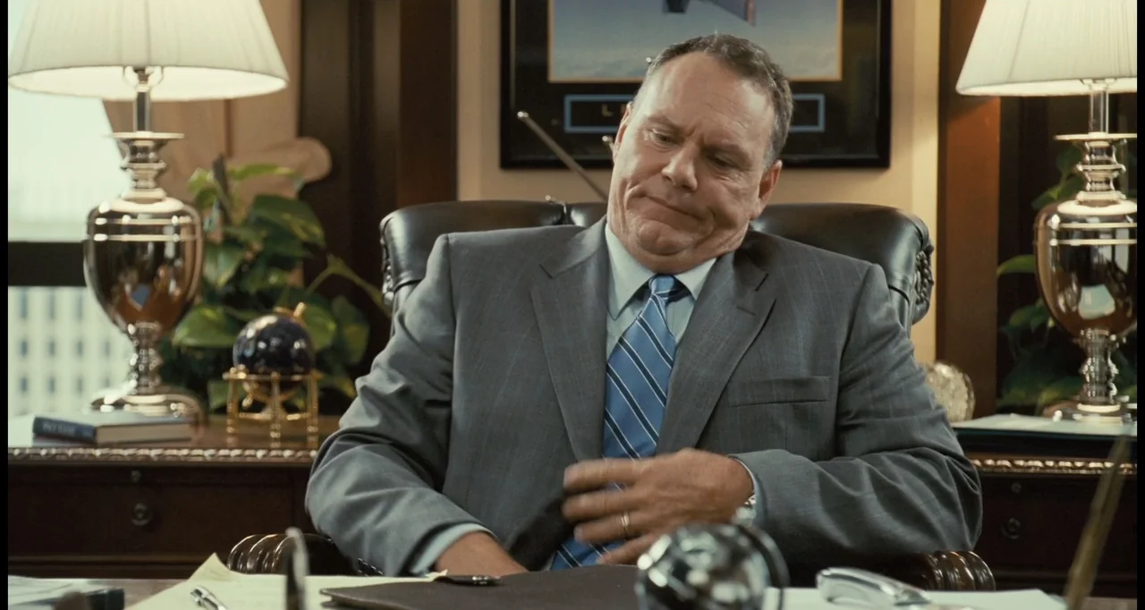 I Love You Phillip Morris (2010) movie still: medium — A well-appointed executive office features dark wood furniture and symmetrical desk lamps on…