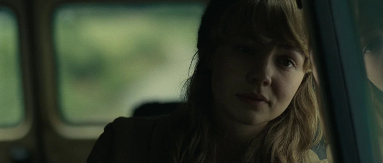 Never Let Me Go (2010) movie still: closeup — The interior of a moving vehicle shows a blurred landscape passing by the window. A young woman looks…