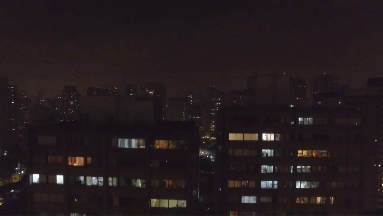 The FIFA Family: A Love Story (2017) movie still: establishing — A dense urban landscape at night features several multi-story apartment blocks in…