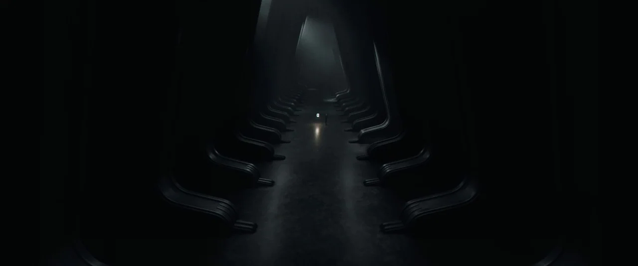 Dune: Part 2 (2024) movie still: wide — A dark, symmetrical hallway features repeating alcoves receding into a deep, indistinct vanishing point. A…