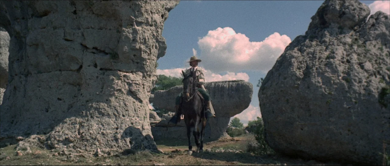 The Mercenary (1968) movie still: wide — A rugged landscape filled with large, weathered stone formations under a clear sky. A man on horseback…