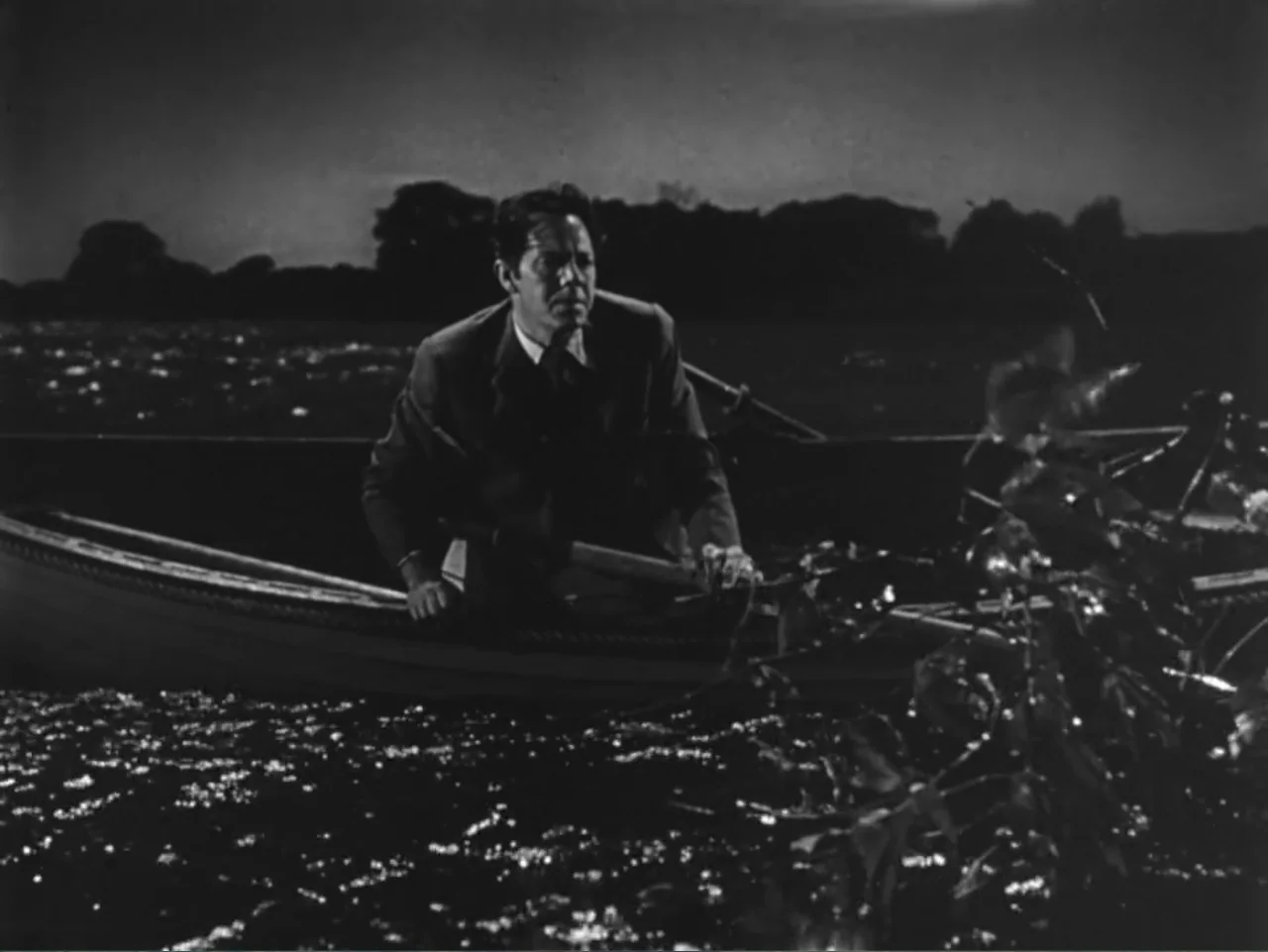House by the River (1950) movie still: medium — A man rows a wooden boat across a dark, ripple-filled body of water at night. The man in a formal…